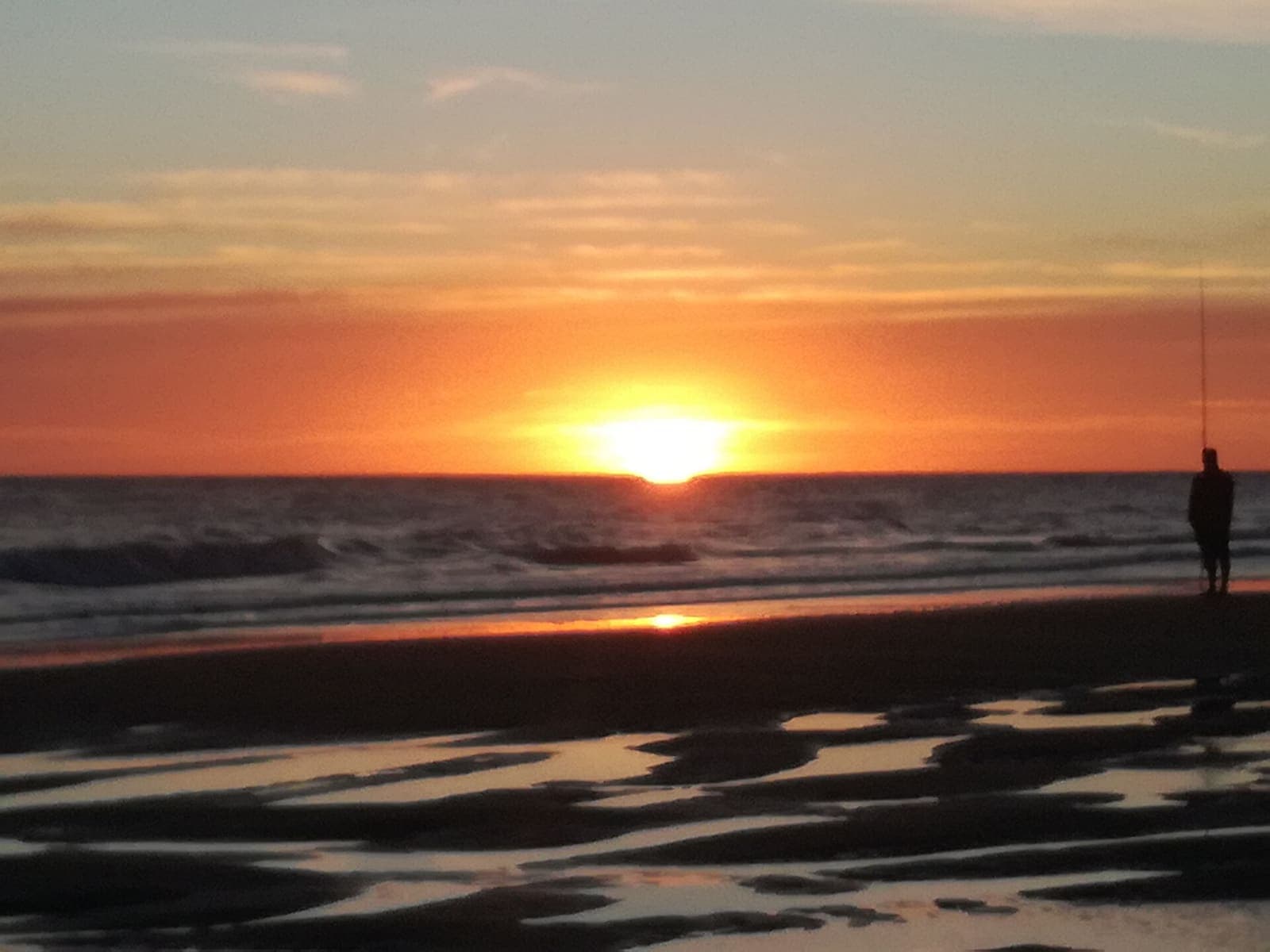 Atardecer sobre el mar en Pehuen Co, con un pescador en la orilla