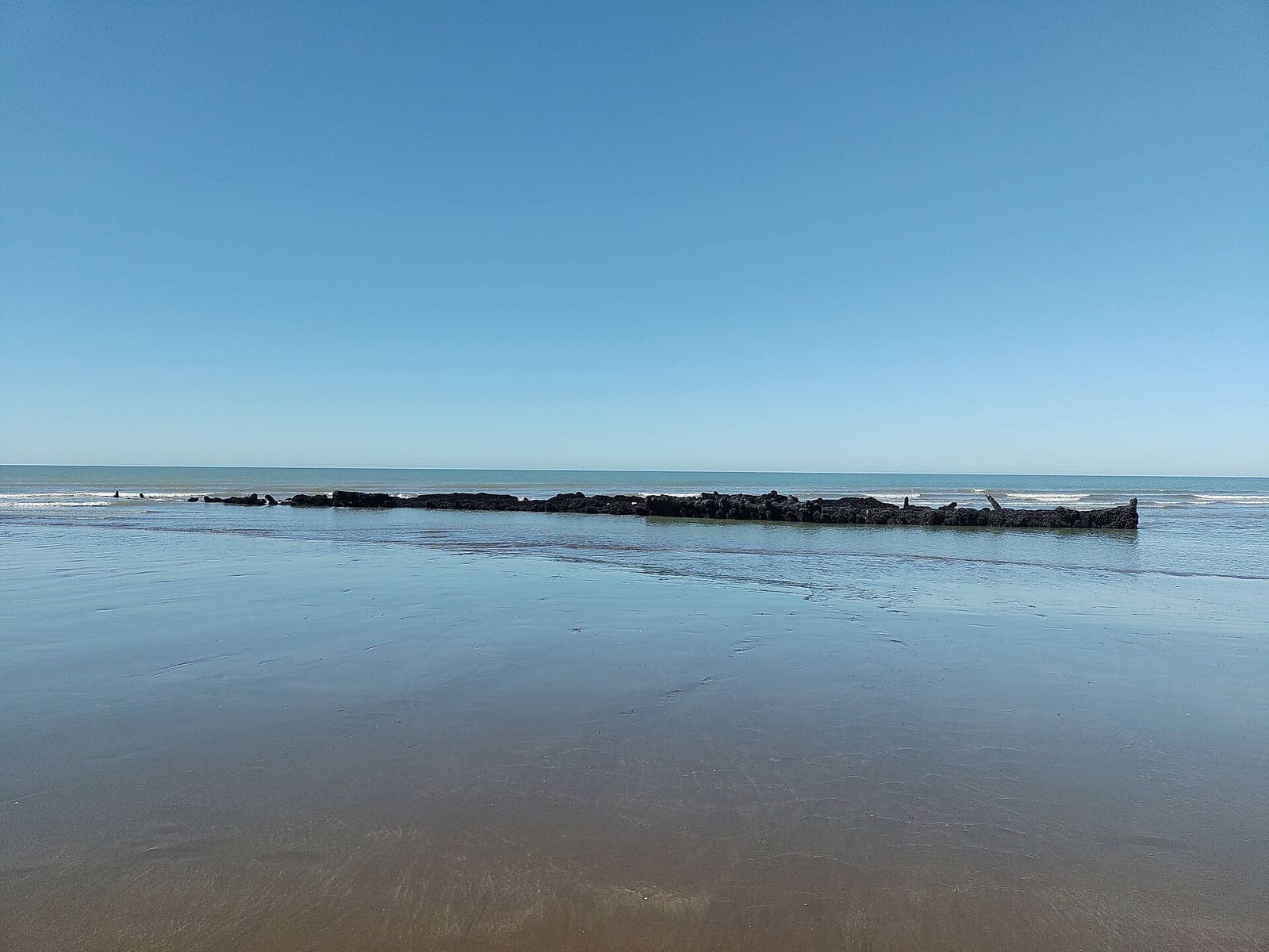 Restos del barco La Soberana asomando en la playa de Pehuen Co